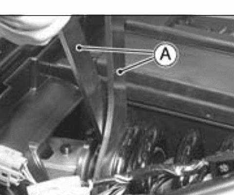Two hook wrenches engaging the locknut and adjusting nut on the rear-shock spring seat.